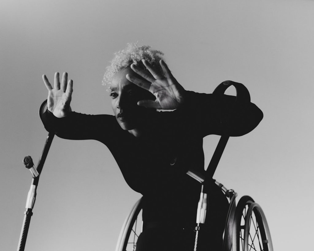 シェパードは車椅子から身を乗り出し、両手と指を広げている。