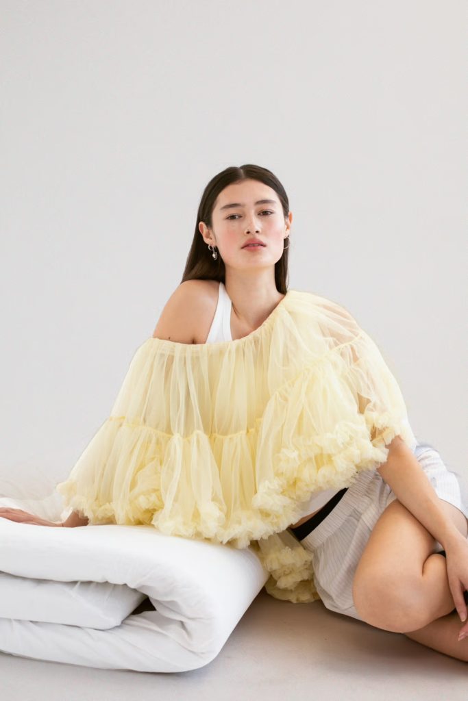 CecilieのケープはNICKLAS SKOVGAARD、タンクトップはTEKLA、ショーツ、ソックス、フープイヤリングとミニフープイヤリングはスタイリストのアーカイブから、ドロップイヤリングはGEORG JENSEN